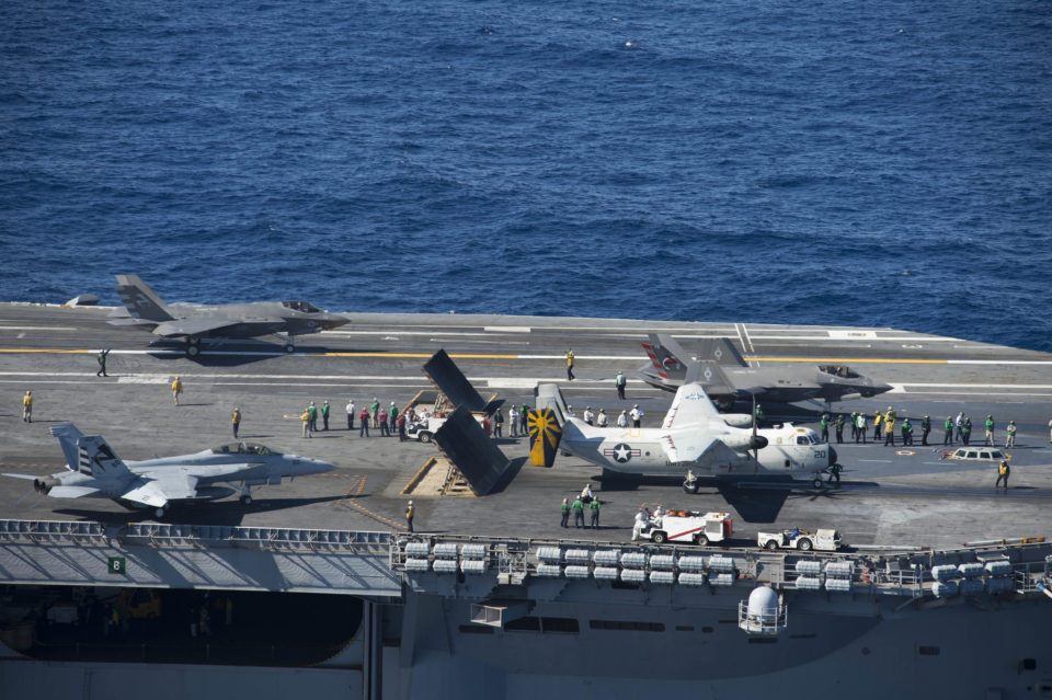 A C-2 Greyhound of VRC-30 and an F-35C Lightning II of VX-23 ready for launching from Nimitz in November 2014; a second F-35C and an F/A-18F Super Hornet sit behind the catapults/